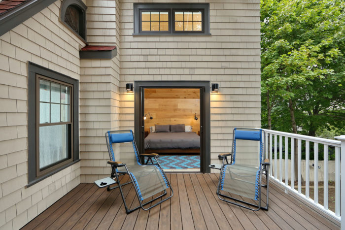 two lounge chairs on second story addition deck in front of bedroom